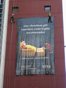 professional industrial abseilers putting up high rise advertising banner